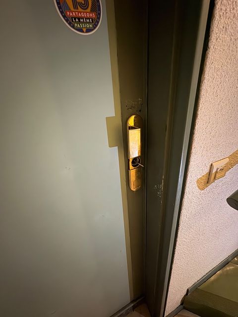Serrure en applique en laiton sur une porte palière, ouverture fine en cours par le cylindre