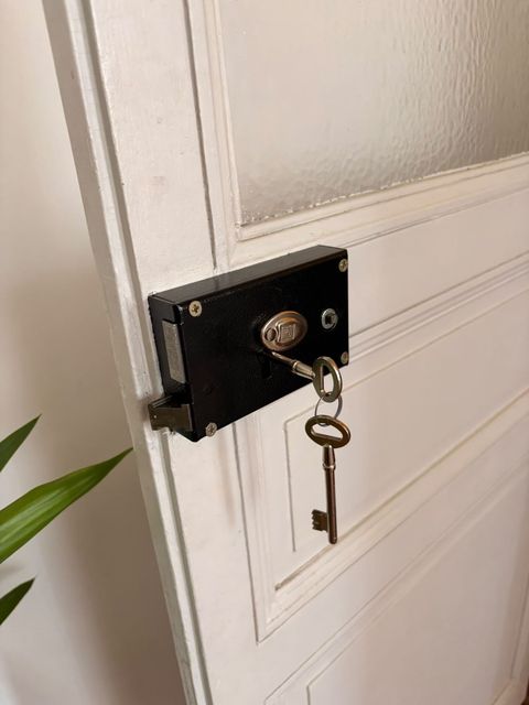 Serrure en applique noire posée sur une porte intérieure ancienne, avec ses clés